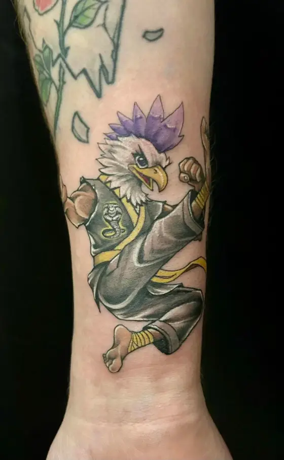 Tatouage couleur d'un aigle en kimono de karaté sur un avant-bras.