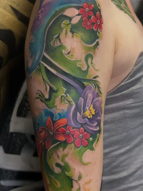 Manchette couleur : lézard vert, fleurs rouges et orchidée mauve sur un bras.