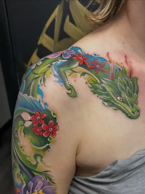 Dragon vert et fleurs rouges couvrant une épaule, en couleur.