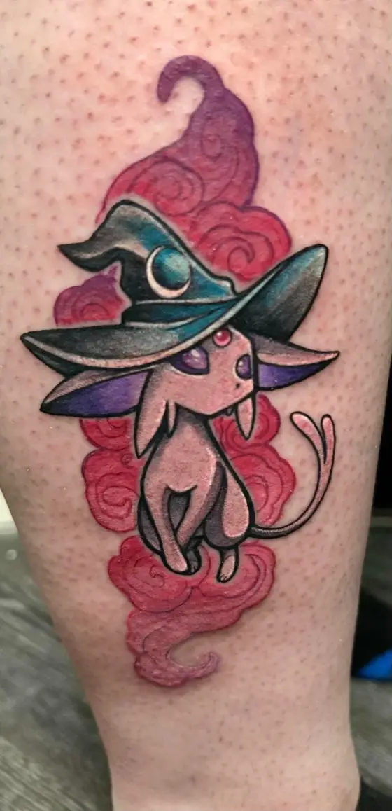 Tatouage couleur d'un Mentali coiffé d'un chapeau de sorcière, entouré de nuages rouges.
